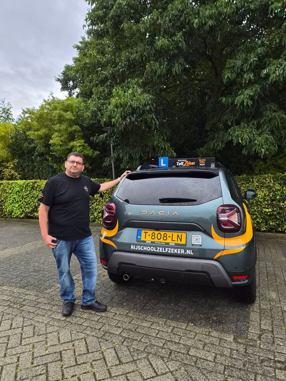 Rani bij de achterkant van de lesauto